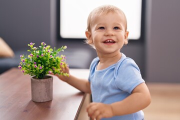 Adorable toddler smiling confident holding plant at home