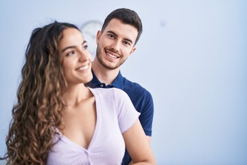 Young hispanic couple hugging each other standing at home