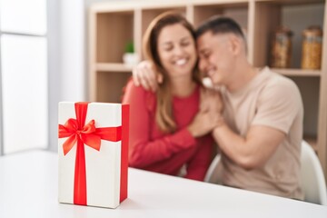 Man and woman mother and son sitting on table with gift at home