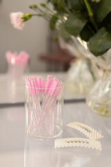 Pink disposable eyebrow or eyelash brushes on dressing table. Vertical