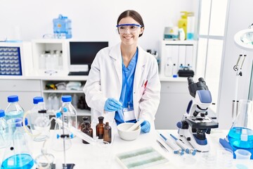 Fototapeta premium Young hispanic woman wearing scientist uniform working at laboratory