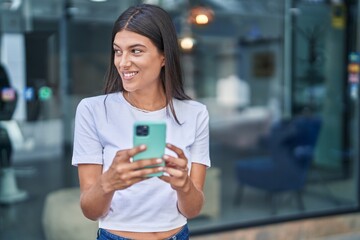 Young beautiful hispanic woman smiling confident using smartphone at street