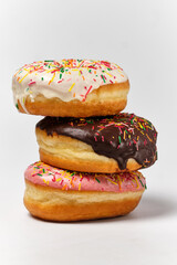 three donuts with different types of glaze on top of each other on a white background, front view