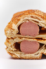 two puffs with sausage and sesame in a cut on a white background, front view