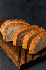 slices of white bread on a kitchen board on a black background, close view