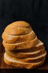 slices of bread on top of each other on a kitchen board, on a black background, front view