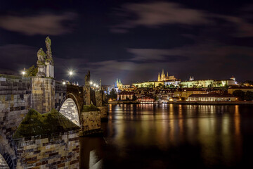 Fototapeta premium The illuminated Charles Bridge and the Prague Castle with the Vltava River during the night.