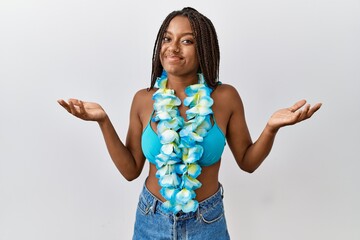 Young african american woman with braids wearing bikini and hawaiian lei clueless and confused...
