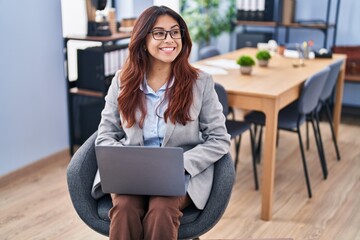 Young hispanic woman business worker using laptop sitting on chair at office