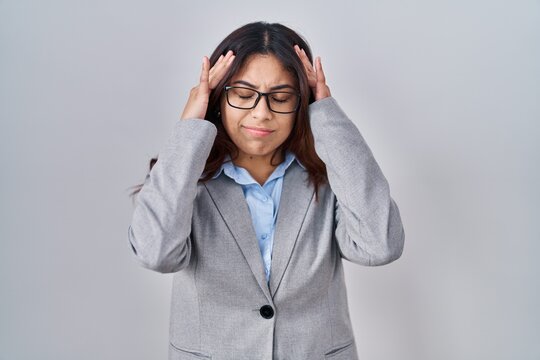 Hispanic young business woman wearing glasses with hand on head for pain in head because stress. suffering migraine.