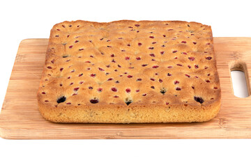Wooden cutting board with freshly baked berry pie on a white background.