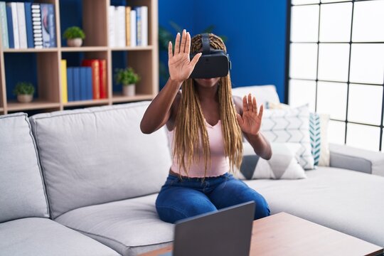 African american woman playing video game using virtual reality glasses at home