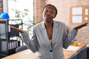 African american woman at the office clueless and confused expression with arms and hands raised....