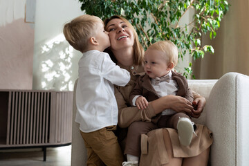 mom with two adorable sons one of whom kisses her on the cheek, mother's day concept