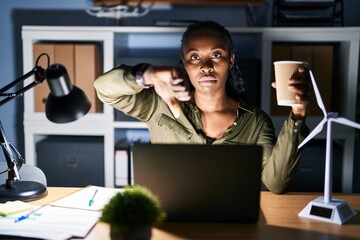African woman working using computer laptop at night looking unhappy and angry showing rejection...