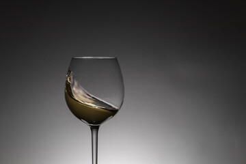 Moving white wine inside a glass. Back lighting, studio shot. Copy space.