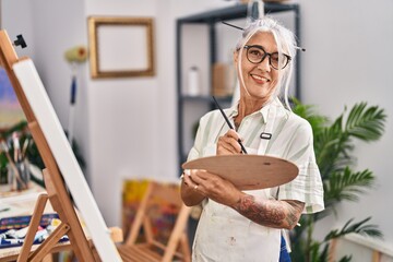 Middle age grey-haired woman artist smiling confident drawing at art studio