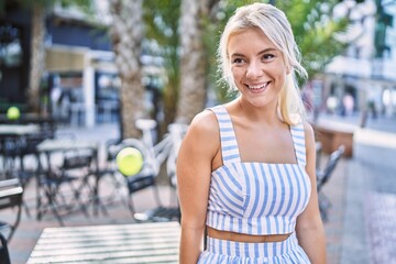 Young blonde girl smiling happy standing at the city.