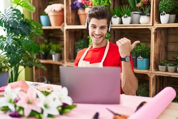 Fototapeta premium Young hispanic man working at florist shop doing video call pointing thumb up to the side smiling happy with open mouth