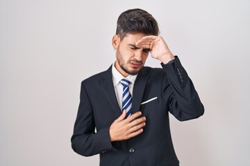 Young hispanic man with tattoos wearing business suit and tie touching forehead for illness and fever, flu and cold, virus sick