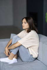 Obraz premium Stressed young woman sitting on sofa at home
