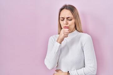 Obraz premium Young blonde woman wearing white sweater over pink background feeling unwell and coughing as symptom for cold or bronchitis. health care concept.