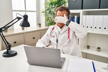 Senior doctor man working on online appointment smiling and laughing with hand on face covering eyes for surprise. blind concept.