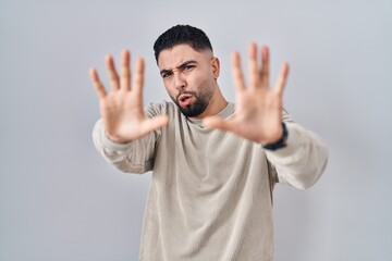 Young handsome man standing over isolated background afraid and terrified with fear expression stop gesture with hands, shouting in shock. panic concept.