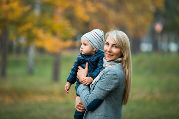 Young happy mother plays with her baby in the park on a sunny autumn day. Happy motherhood and...