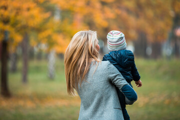 Young happy mother plays with her baby in the park on a sunny autumn day. Happy motherhood and...