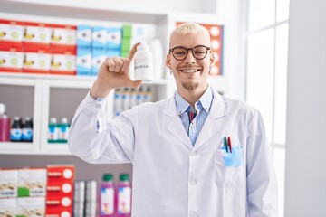 Young caucasian man pharmacist holding pills bottle at pharmacy