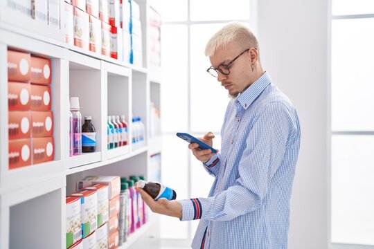 Young caucasian man customer making photo to medication bottle at pharmacy