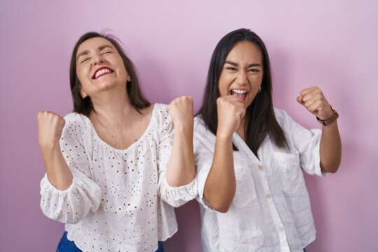 Hispanic mother and daughter together celebrating surprised and amazed for success with arms raised and eyes closed. winner concept.