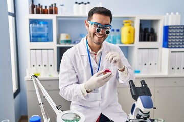 Young hispanic man scientist looking gemstone by magnifying glasses at laboratory