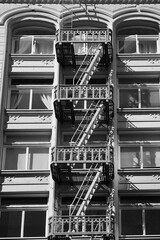 Metalic stairs used for emergency outside a residential building from America. Vintage style staircase architecture, black and white photo.