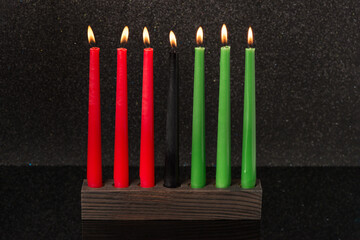 Kwanzaa festival concept with seven candles red, black and green in candlestick on black...