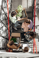 Vertical anticipating busy students carrying stuff in boxes on stairs while move in new college campus. High angle view
