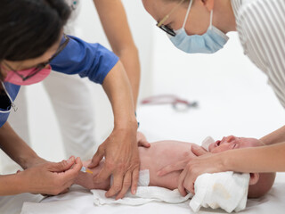 Obraz na płótnie Canvas Baby beeing vaccinated by pediatrician in presence of his mother. Preventive vaccination against Diphtheria, whooping cough, tetanus, hepatitis, haemophilus influenzae, pneumococcus, poliomyelitis