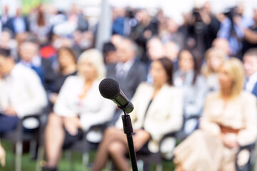 Fototapeta na wymiar Business conference event or corporate presentation, microphone in the focus, blurred audience in the background