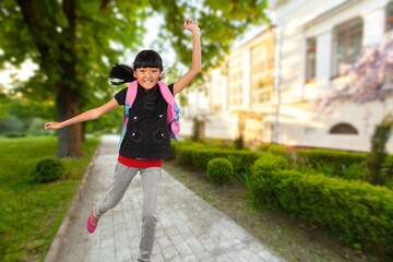 Happy small school child running on street.