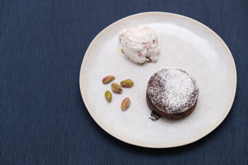Obraz na płótnie Canvas Brown chocolate soufflé with ice cream and pistachios decoration on a plate