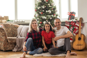 Obraz na płótnie Canvas Young happy family while celebrating Christmas at home.