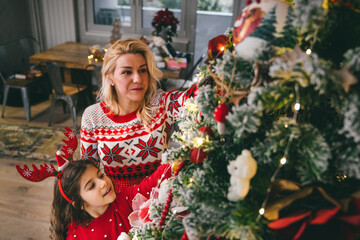 Mother and daughter decorating Christmas tree spending lovely time together