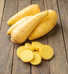 Raw mandioquinha or arracacha with slices over wooden table