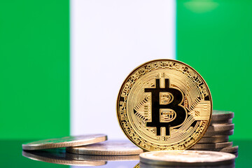 Gold metal coin Bitcoin on the background of the flag of Nigeria. Concept for investors in...