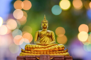 Close up golden Buddha meditation statue with light bokeh 
