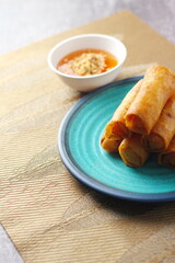 Fried spring rolls on a blue plate and spicy sauce