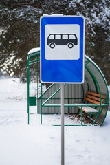 Bus stop in the middle of a beautiful winter road in the middle of the forest with a bus stop sign.
