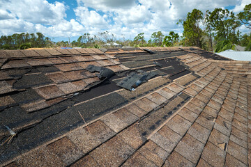 Fototapeta Damaged house roof with missing shingles after hurricane Ian in Florida. Consequences of natural disaster obraz