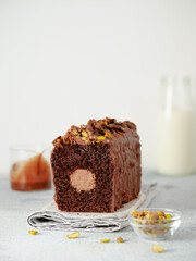 Travel Cake or Tube Cake or Voyage Cake filled center tube ganache and topped chocolate icing and pistachio. Chocolate loaf cake with chocolate cream-cheeese filled center. Copy space. Vertical